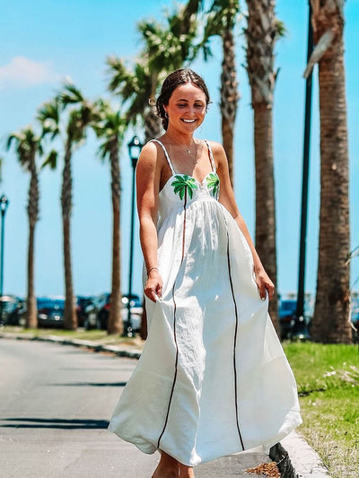 Zoom sur le haut de la robe blanche avec motif palmier et fines bretelles.