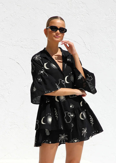 Robe tunique noire avec imprimés blancs abstraits de style bohème, manches amples et col en V, vue de face.